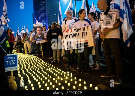 Israele. 22nd Apr, 2023. I membri della famiglia in lutto tengono una foto dei loro cari accanto a migliaia di candele “Yom HaZikaron” per la Giornata commemorativa dei soldati caduti israeliani e delle vittime degli attacchi terroristici durante una protesta contro la revisione giudiziaria a Tel Aviv. Apr 22th 2023. (Matan Golan/Sipa USA). Credit: Sipa USA/Alamy Live News Foto Stock