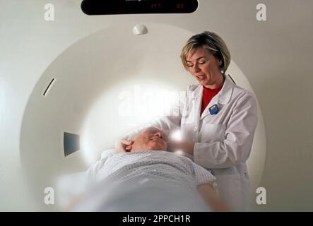 Tecnico che prepara un uomo anziano per una RM Foto Stock