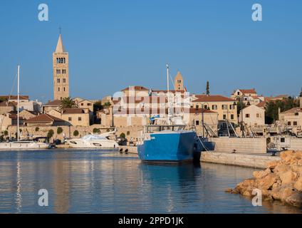 Rab, Croazia - 24 agosto 2022: Una vista mozzafiato dell'isola di Rab, Croazia con un mare punteggiato da navi e le sue iconiche torri chiesa a cupola grigia sur Foto Stock