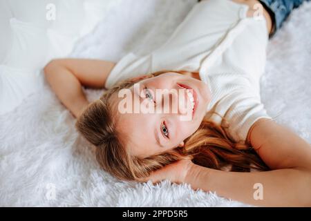 Ragazza felice che si rilassa sul letto di pelliccia a casa Foto Stock
