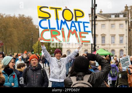 Extinction Rebellion 'The Big One', organizzato fine settimana di protesta. L'uomo tiene una grande bandiera di protesta fuori Westminster. Aprile, 2023. Foto Stock