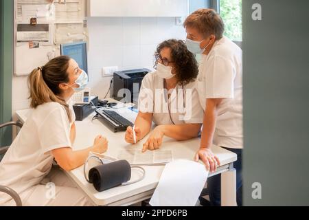 Infermieri che indossano maschere protettive per il viso che discutono insieme in clinica Foto Stock