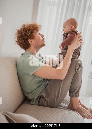 Padre che passa del tempo con il figlio sul divano a casa Foto Stock