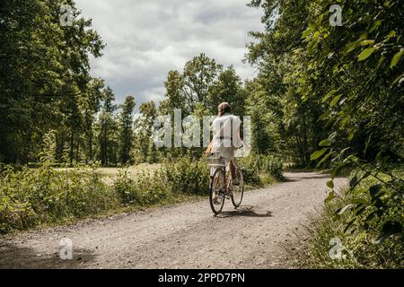 Donna in bicicletta su strada sterrata Foto Stock