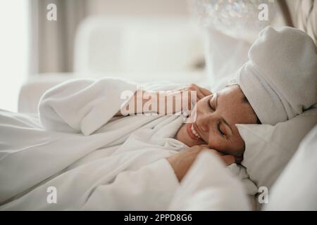 Donna felice che si rilassa in camera da letto a casa Foto Stock