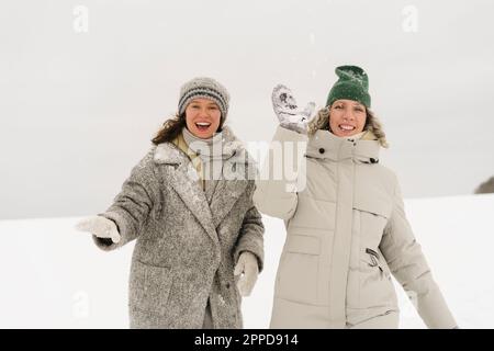 Amici allegri che si divertono a gettare la neve in inverno Foto Stock