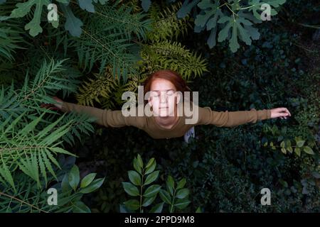 Ragazza in piedi con le braccia distese tra le piante Foto Stock