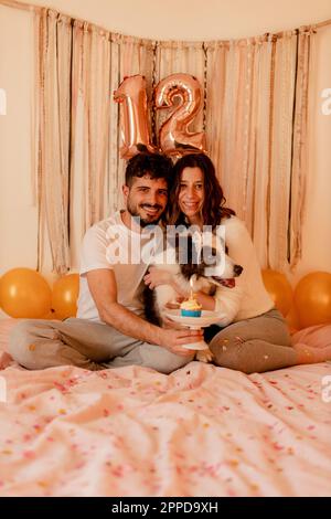 Felice uomo e donna che festeggia il compleanno del cane collie di bordo a casa Foto Stock