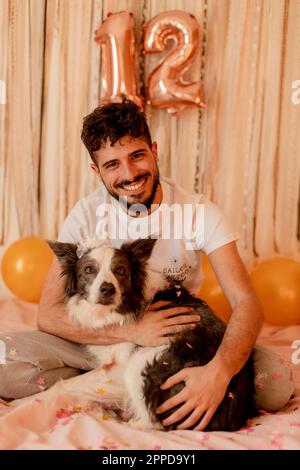 Felice giovane uomo che celebra il compleanno del cane di collie di bordo Foto Stock