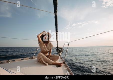 Donna sorridente che indossa un cappello seduto sulla barca a vela Foto Stock