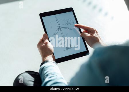 Uomo d'affari con turbina eolica che lavora su un tablet PC in ufficio Foto Stock