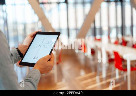 Mani di un uomo d'affari con design a turbina eolica su un tablet PC in ufficio Foto Stock