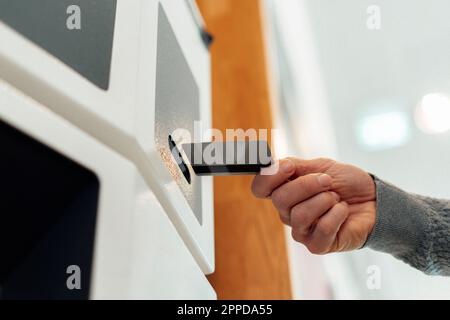 Mani di un uomo che inserisce la carta nel bancomat Foto Stock