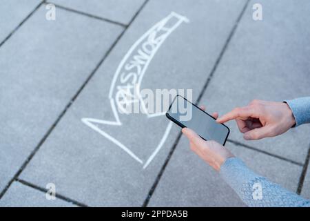 Uomo che utilizza uno smartphone con una freccia di testo sul sentiero Foto Stock