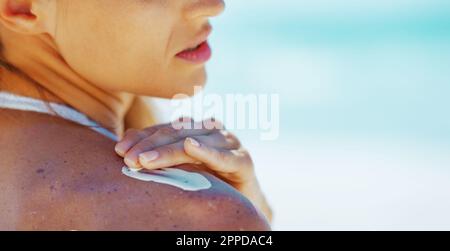 Primo piano sulla giovane donna che applica crema solare schermo Foto Stock