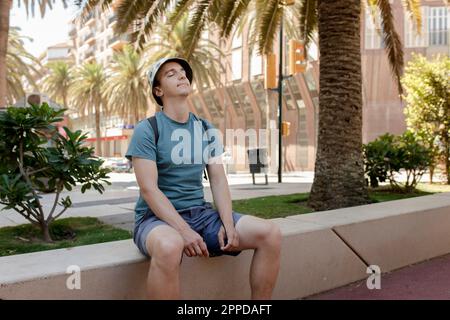 Uomo che indossa un cappello di panama seduto con gli occhi chiusi Foto Stock