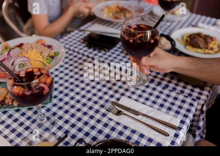 Mano dell'uomo che tiene un bicchiere di sangria Foto Stock