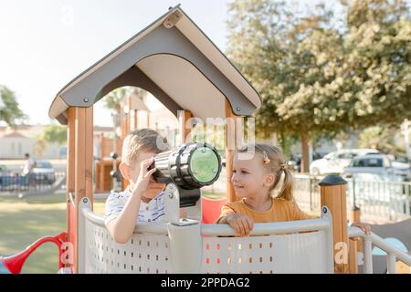 Ragazza sorridente con fratello che guarda attraverso il telescopio Foto Stock