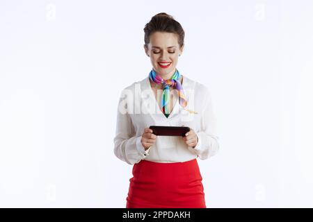 donna sorridente e moderna, che si guarda su sfondo bianco in uniforme utilizzando le applicazioni per smartphone. Foto Stock