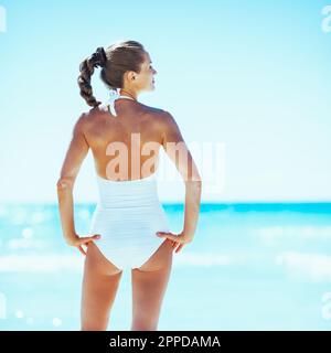 giovane donna in piedi sulla spiaggia. vista posteriore Foto Stock