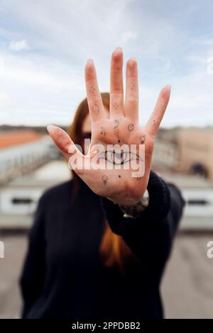 Donna che mostra palma con occhio tatuaggio Foto Stock