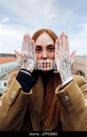 Donna che mostra mano tatuata sul terrazzo Foto Stock