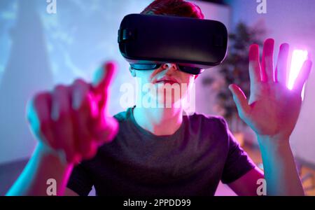 Giovane uomo che indossa occhiali VR gesturanti a casa Foto Stock