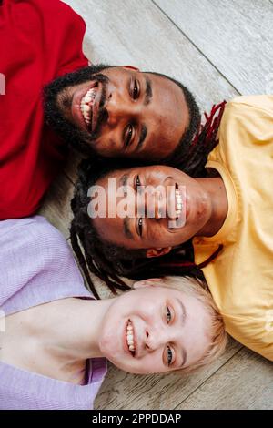 Amici multirazziali felici sdraiati sul pavimento a casa Foto Stock