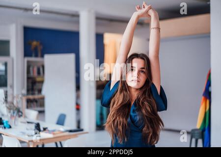 Giovane donna d'affari con le braccia sollevate in piedi in ufficio Foto Stock