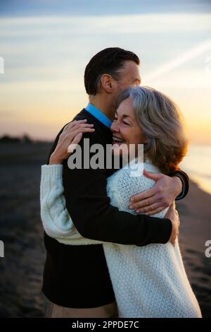 Coppia matura che si abbraccia in spiaggia Foto Stock