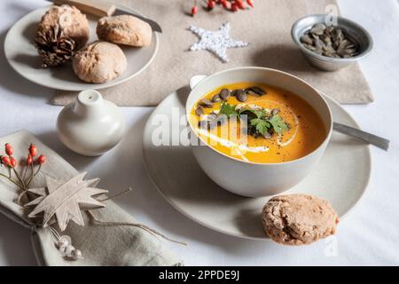 Shot studio di ciotola di zuppa di zucca con panini fatti in casa nel contesto di Natale Foto Stock