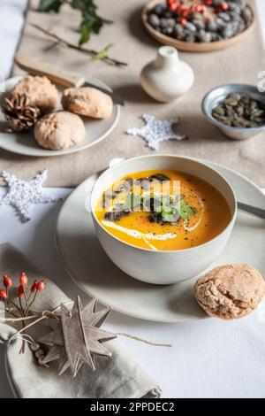 Shot studio di ciotola di zuppa di zucca con panini fatti in casa nel contesto di Natale Foto Stock