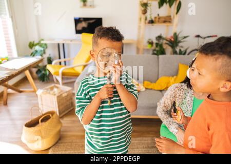 Ragazzo che guarda attraverso la lente di ingrandimento a casa Foto Stock