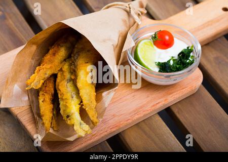 Acciughe fritte in padella con salsa cremosa al formaggio, verdure Foto Stock