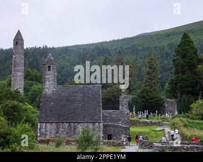 Le antiche rovine della città monastica di Glendalough, tra cui la Torre rotonda e Saint Kevin's Kitchen, nel Parco Nazionale delle Montagne di Wicklow, Irlanda. Foto Stock