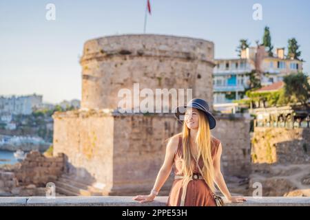 Donna turistica sullo sfondo della Torre Hidirlik di Antalya sullo sfondo della baia mediterranea dell'antico quartiere di Kaleici, Turchia Foto Stock