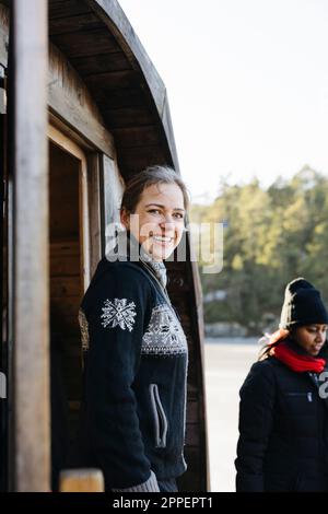 Donna sorridente in piedi di fronte alla sauna Foto Stock