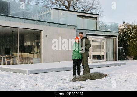 Uomo e donna in piedi di fronte a casa in inverno Foto Stock