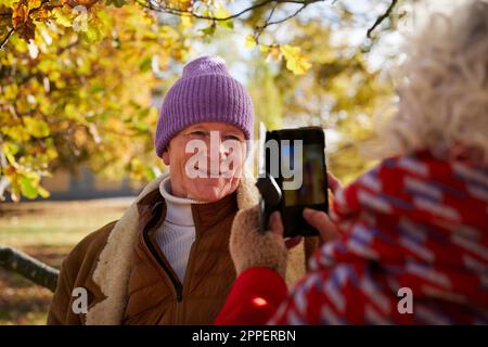 Donna che fotografa un uomo sorridente Foto Stock