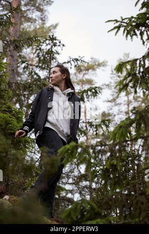 Basso angolo di visione della donna in piedi nella foresta Foto Stock