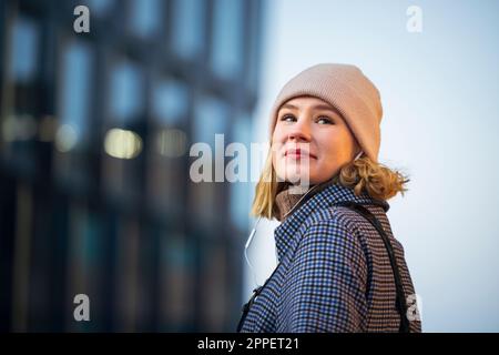 Sorridente giovane donna che indossa le cuffie all'aperto Foto Stock