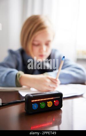 Gioco elettronico sul tavolo, ragazza che fa i compiti in background Foto Stock