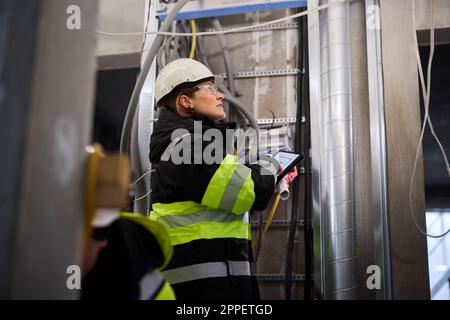 Ingegnere donna che utilizza un tablet digitale in cantiere Foto Stock