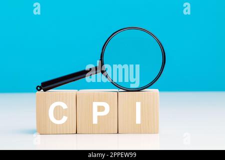 CPI - Consumer Price Index symbol.Letter Block in word CPI abbreviazione dell'indice dei prezzi al consumo con una lente d'ingrandimento su sfondo blu.copy space. Foto Stock