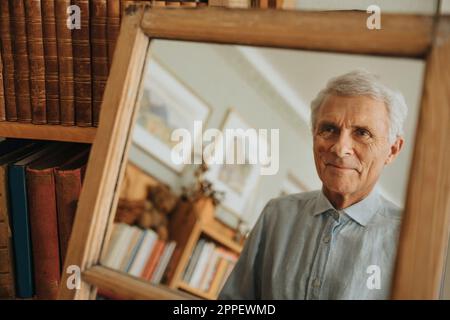 Uomo anziano che guarda in specchio a casa Foto Stock