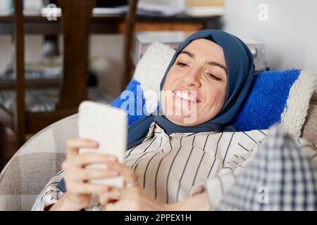 Donna sul divano utilizzando il telefono cellulare Foto Stock