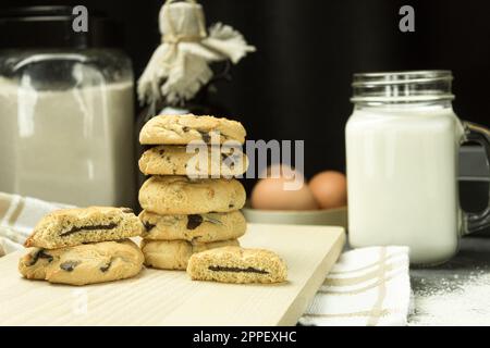 Biscotti appena sfornati con cioccolato su una teglia da forno. I biscotti con scaglie di cioccolato sono impilati. Spazio per il testo Foto Stock