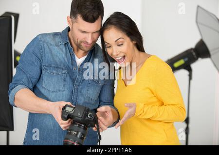 fotografo che rivede le foto e le mostra al modello femminile positivo Foto Stock