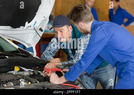 i meccanici si preparano a utilizzare i cavi ponte sull'auto Foto Stock