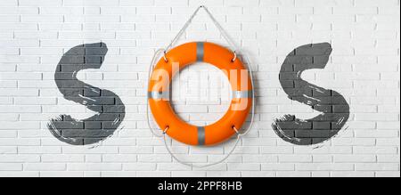 Messaggio SOS composto da salvaboa e lettere su muro di mattoni bianchi. Design del banner Foto Stock